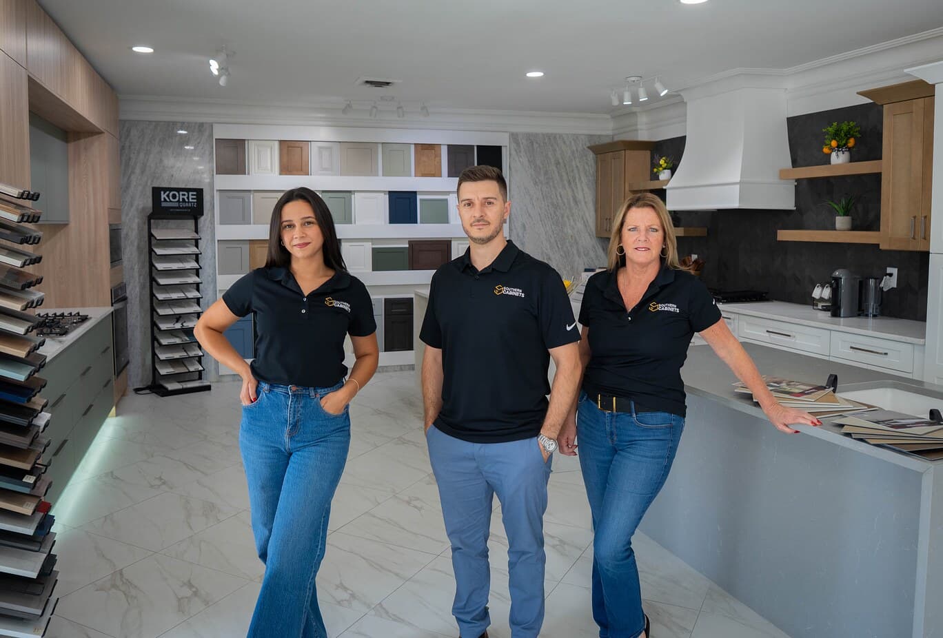Three Southern Cabinets team members in the showroom, with cabinet door sample displays and a display kitchen behind them